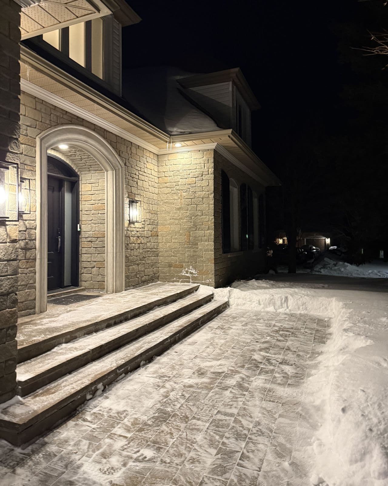 Cleared front steps and a swept walkway at a house on a winter evening